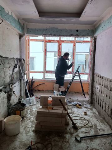 Pencere montajı yapan usta, sıvası dökülmüş oda